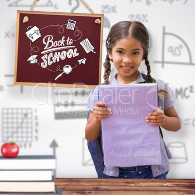 Composite image of cute pupil smiling at camera holding notepad