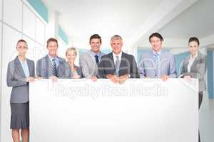 Composite image of smiling business team holding poster