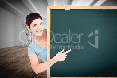 Composite image of beautiful brunette pointing at a blank panel