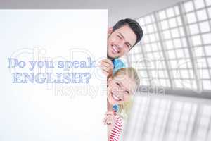 Composite image of smiling young couple hiding behind a blank si