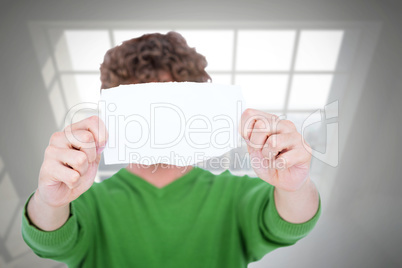 Composite image of man holding blank paper in front on face