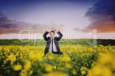 Composite image of businessman sitting in lotus pose with hands