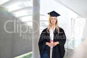 Composite image of blonde student in graduate robe holding her d