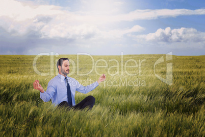 Composite image of businessman in suit sitting in lotus pose