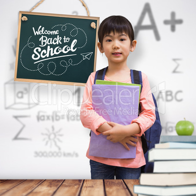 Composite image of cute pupil looking at camera holding notepad