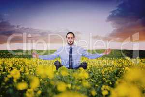 Composite image of businessman in suit sitting in lotus pose