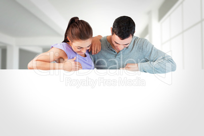 Composite image of young couple looking down a wall