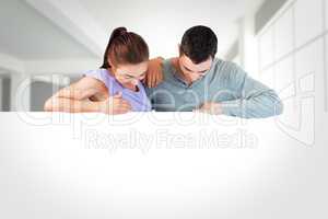 Composite image of young couple looking down a wall
