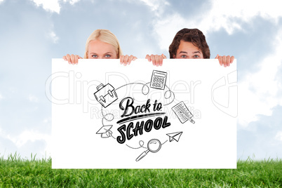 Composite image of happy couple hiding behind a whiteboard