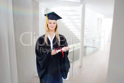 Composite image of blonde student in graduate robe holding up he