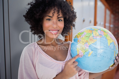 Composite image of happy woman pointing to globe