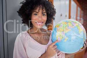 Composite image of happy woman pointing to globe