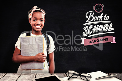 Composite image of little girl holding folders in school corrido