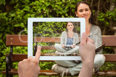 Composite image of hand holding tablet pc