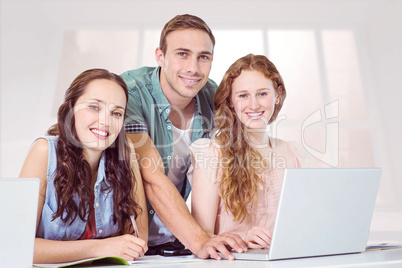 Composite image of fashion students using laptop