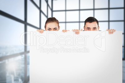 Composite image of business partners hiding behind a sign