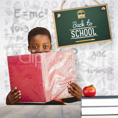 Composite image of cute boy reading book in library