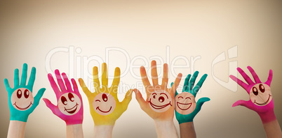 Composite image of hands with colourful smiley faces