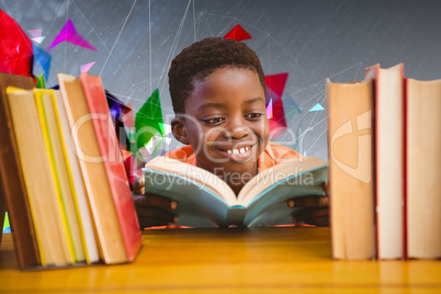 Composite image of cute boy reading book in library