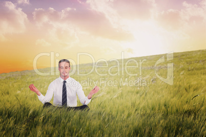 Composite image of businessman meditating in lotus pose