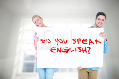 Composite image of smiling young couple holding a blank sign