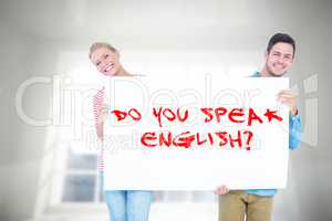 Composite image of smiling young couple holding a blank sign