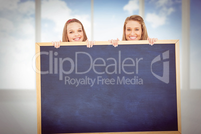 Composite image of close up of young women behind a blank sign