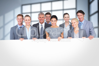 Composite image of smiling business team holding poster