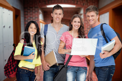 Composite image of a smiling group of students holding a laptop