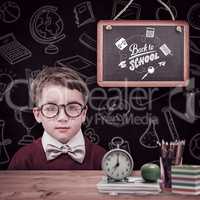 Composite image of cute schoolboy wearing reading glasses