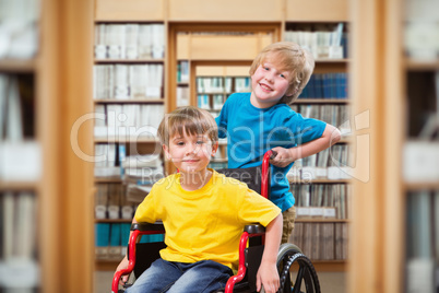 Composite image of happy boy pushing friend on wheelchair