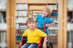 Composite image of happy boy pushing friend on wheelchair