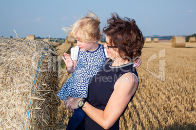 Woman with child on the field with straw bales