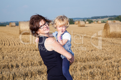Woman with child on the field with straw bales