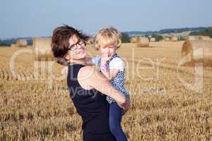 Woman with child on the field with straw bales