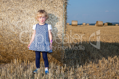 Girl stands in front Strohrolle on the field