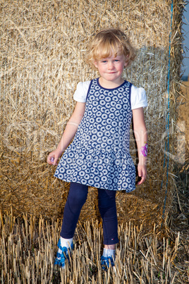 Girl stands in front Strohrolle on the field