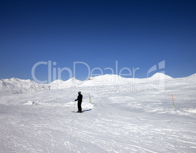 Skier on ski slope at sun day