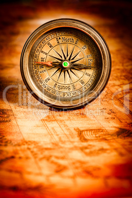 Vintage compass lies on an ancient world map.