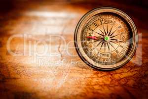 Vintage compass lies on an ancient world map.