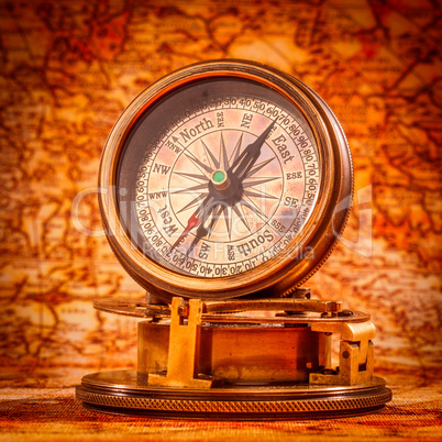 Vintage compass lies on an ancient world map.