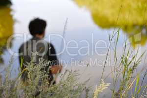 Blurred silhouette of fisherman on the river on a clear summer d