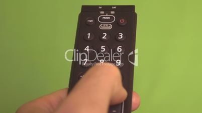 Frontal shot of male hand changing channels with remote control on a green screen.