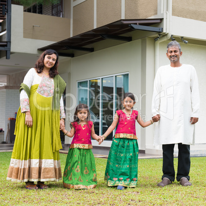 Indian family holding hands outside new home