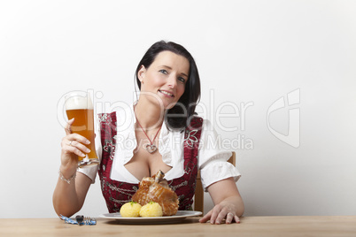 Bayerische Frau in einem Dirndl mit Schweinshaxe