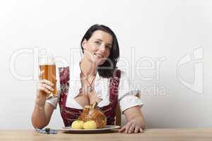 Bayerische Frau in einem Dirndl mit Schweinshaxe
