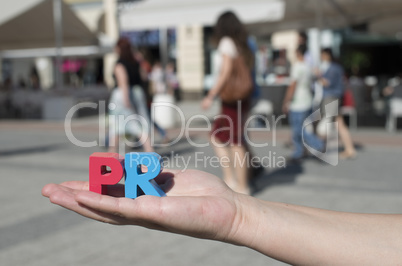 Women hold wooden letters PR