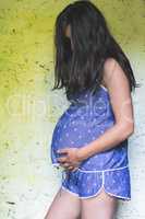 Pregnant women in front of old colored wall.