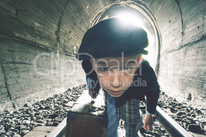 Child walking on railway road with vintage siutcase.