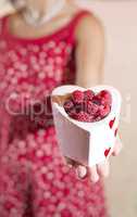 Woman holding a cup of raspberries